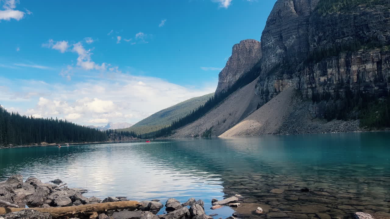 Paesaggio montano, persone che remano piccole barche su un lago dalle acque turchesi.