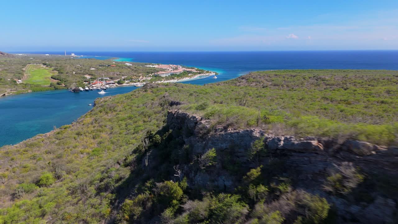 Aerial dolly reveal of Seru Kabritu with resort in the background, capturing Curacao's beautiful coastal landscape