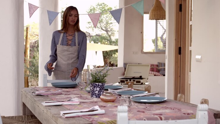 Young woman preparing table on a terrace for a dinner party, shot on R3D