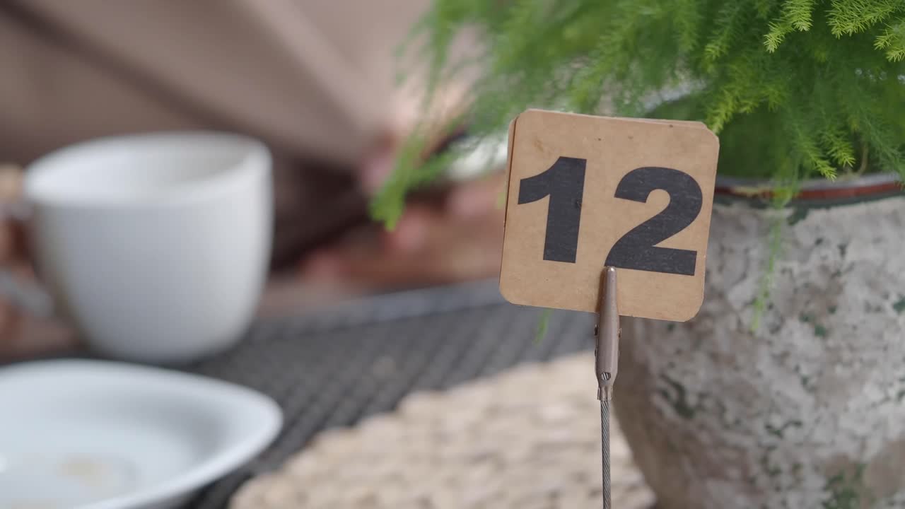 Primo piano del tavolo numero 12 con tazza di caffè e pianta.