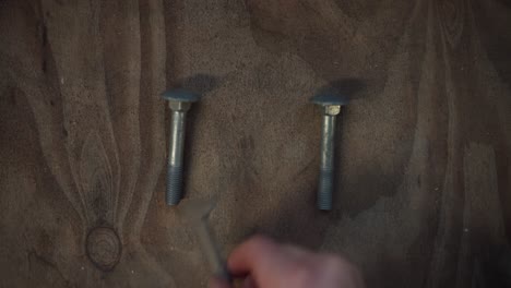 la mano de un hombre ha arreglado tuercas y pernos en la mesa en indre fosen, condado de trondelag, noruega - de cerca