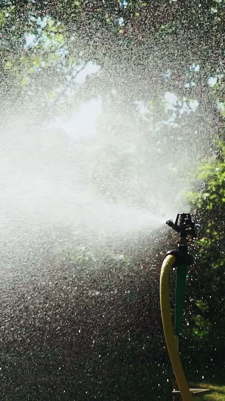 Irrigation equipment. Automatic agricultural sprinkler watering system for plants and lawn. Slow motion. Vertical video