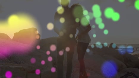 Animation-of-light-spots-over-african-american-couple-at-beach