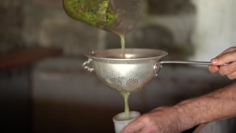 verter jugo de uva recién triturado en un frasco de prueba a través de un viejo tamiz de aluminio