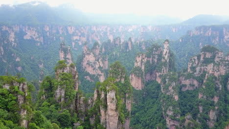 Dramatic-rock-spires-extend-into-misty-distance,-Hunan-China-aerial