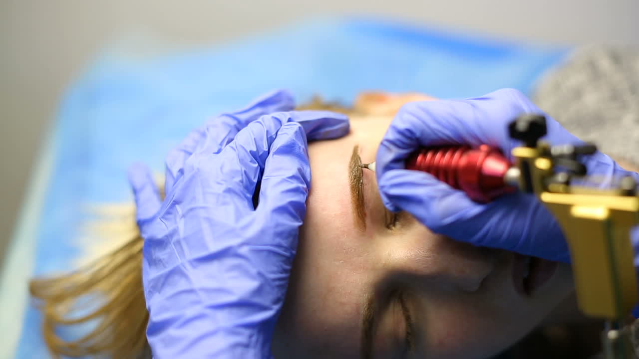 Tattooist making permanent make-up. Close up of specialist doing eyebrow tattooing for female
