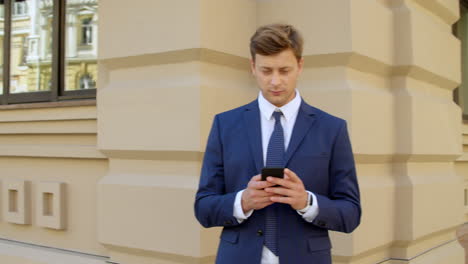 Thinking-business-man-using-mobile-phone-outdoors.-Focused-executive-man