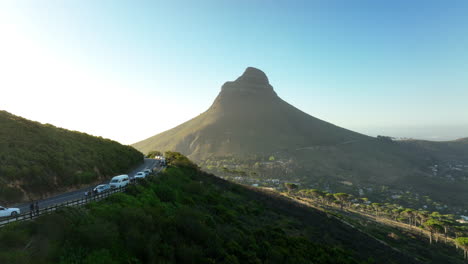 Amazing-shot-of-Lions-Head-mountain-towering-above-residential-neighbourhoods-of-city.-Cars-parked-along-road.-Cape-Town,-South-Africa