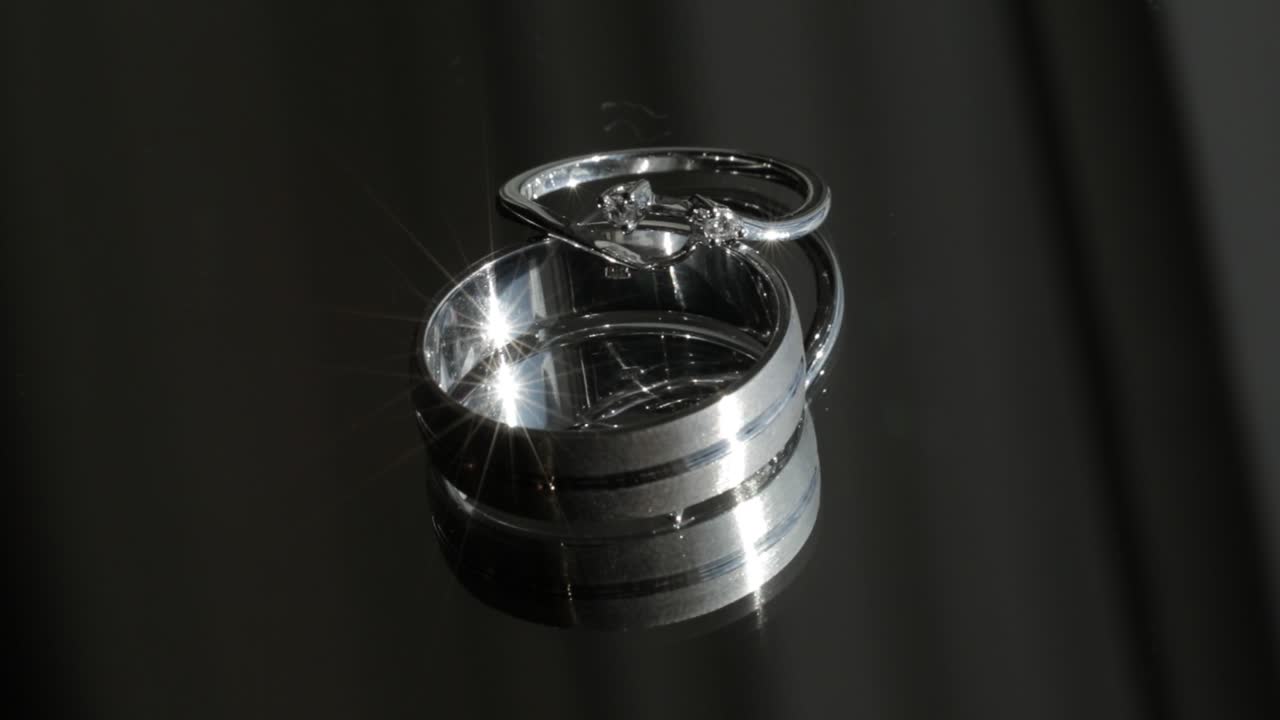 красивые обручальные кольца мерцают светом, покоясь на зеркале