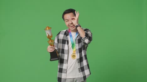 hombre sosteniendo el trofeo y la medalla con orgullo