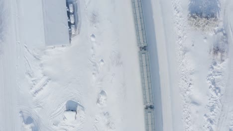 a birds eye view of a snowy train travelling through the forests in the canadian shield