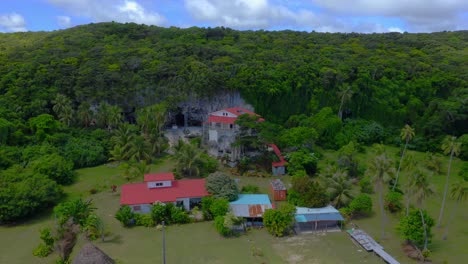 From-the-drone's-perspective,-a-stunning-house-carved-into-a-rocky-outcropping-on-the-coastline-of-Lifou-island,-is-seen