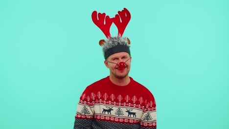 Cheerful-lovely-30s-years-old-man-wears-red-New-Year-sweater-and-hat-smiling,-looking-at-camera