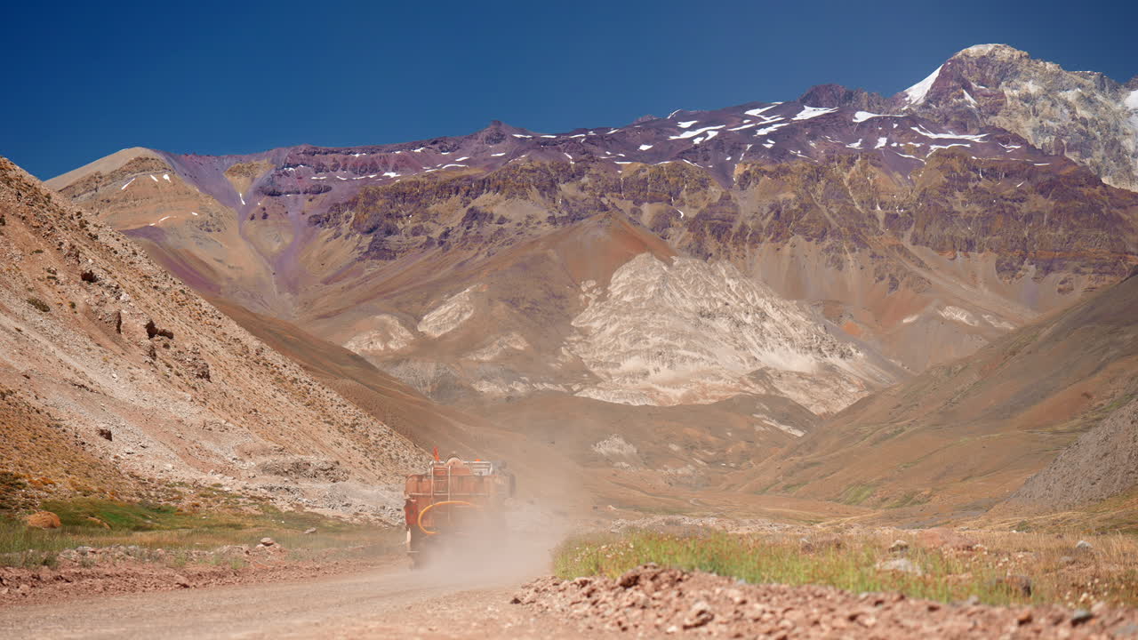 Water truck drives by on dusty dirt road in Andes mountains for mining use