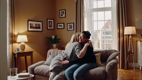 two women sharing a loving embrace on a sofa in their living room