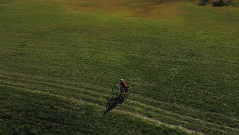 One-Woman-cycling-with-a-touring-bike-in-a-green-field-in-autumn-nature-in-Bavaria-with-alps