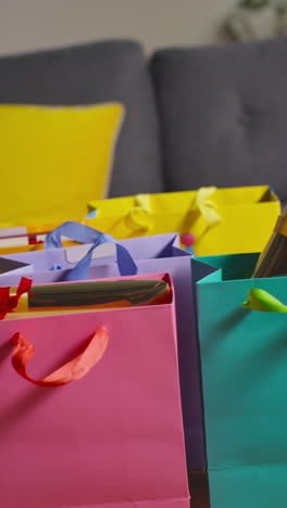 vertical video of gift wrapped presents in colourful bags with tag on table in lounge at home