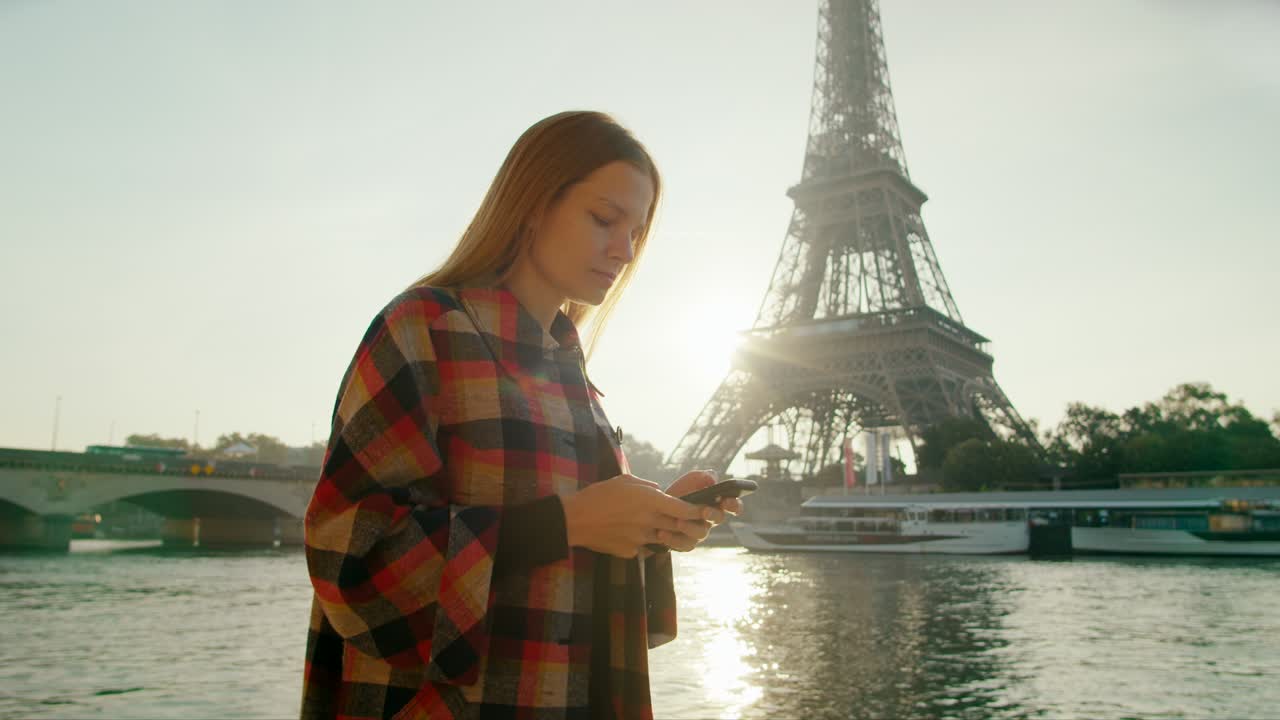 una mujer elegante usa una aplicación de teléfono inteligente caminando cerca de la torre eiffel en parís, francia