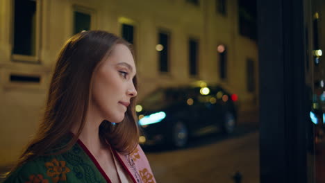 una dama eligiendo un vestido de novia mirando a través de la vitrina de la tienda en un primer plano nocturno de la ciudad