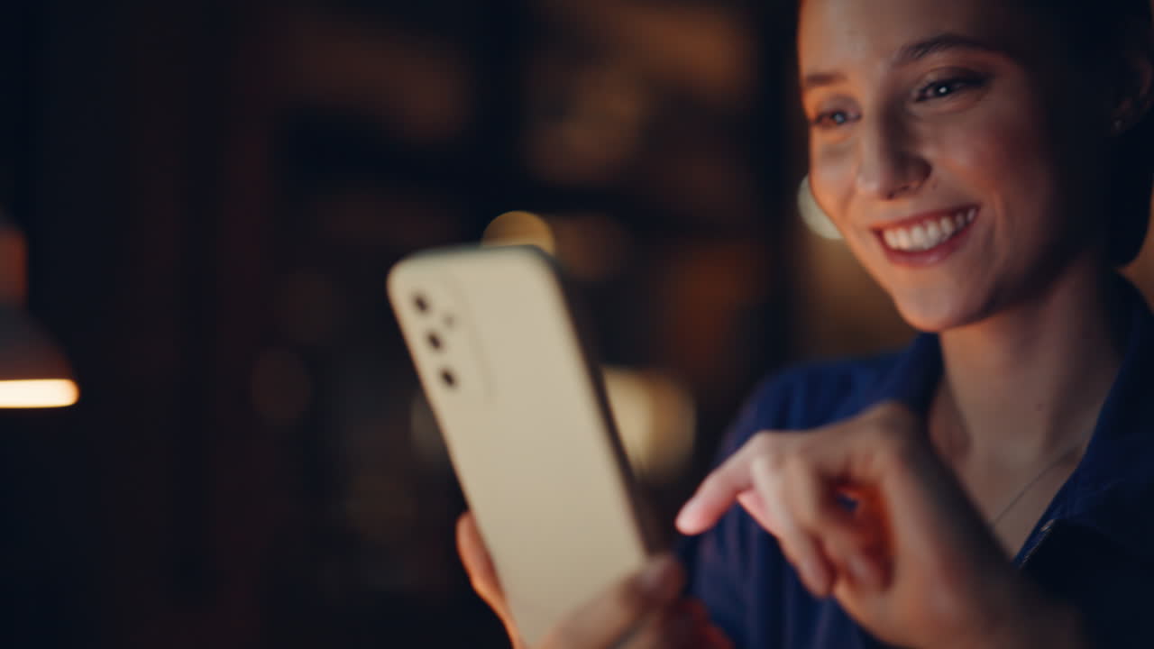 Startuper hands scrolling phone news feed at night office closeup. Smiling woman