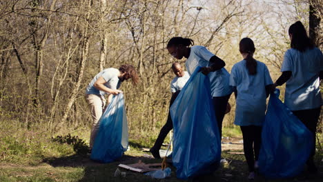 african american girl picking up trash with a long claw and garbage bags