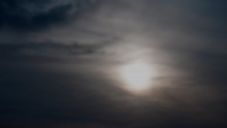 4k time lapse of twilight sunset surrounded by light clouds turning into darkness as the sun sets downwards behind the vapour silky sheer rolling change in the sky