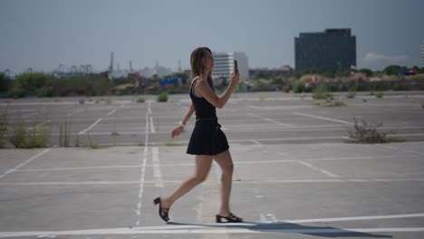 woman walking in a parking lot with a phone