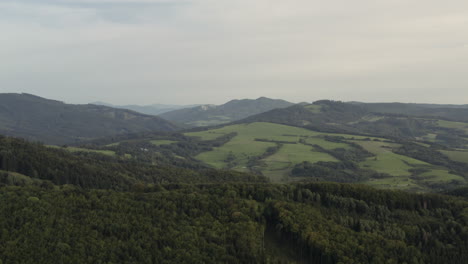 sideways aerial shot of hilly green forests and fields, czech republic