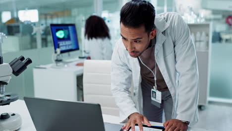 Scientist working on a laptop in a modern laboratory