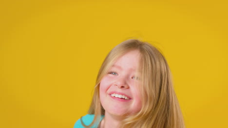 Retrato-De-Estudio-De-Una-Chica-Con-El-Pelo-Largo-Riendo-Y-Girando-Sobre-Fondo-Amarillo