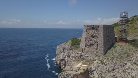 one tourist sits atop ancient fortification on punta campanella, italy