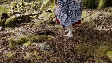 mujer chamán caminando descalza de derecha a izquierda en un suelo de selva tropical cubierto de musgo mientras agradece a sus antepasados por su abundancia