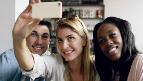 diverse group friends taking selfie self portrait in cafe using smartphone