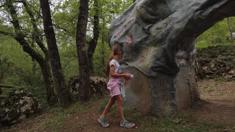 a young girl in top and shorts finds strange markings on large stones