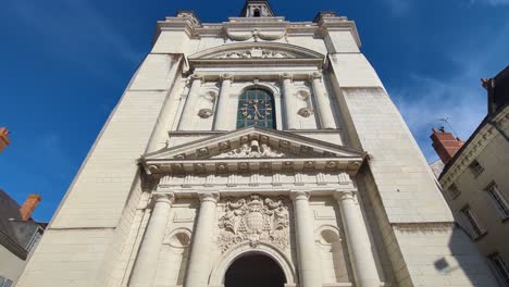 wide view of historic old religious imposing church building with insignia and clock with blue sky background in saumur, france, europe 4k