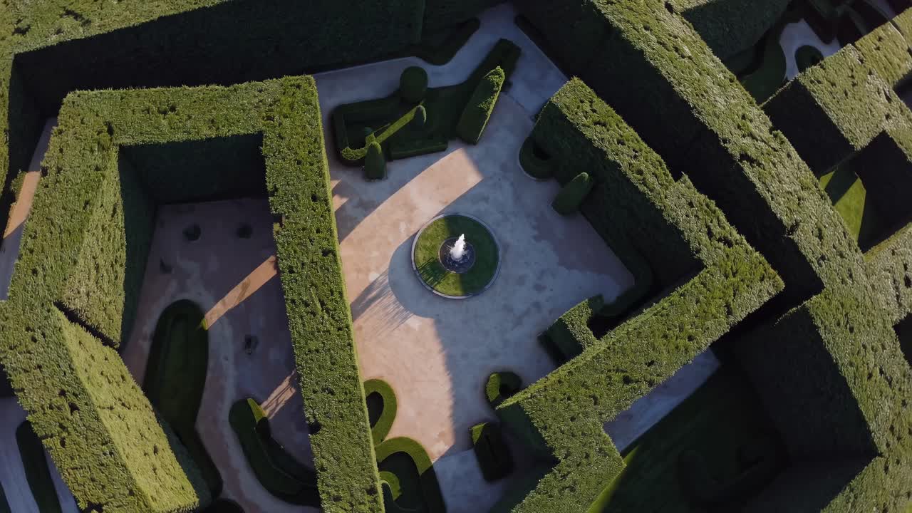 Aerial view of a lush green maze garden with geometric patterns, captured in a video