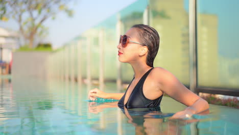 Mujer-Exótica-Sexy-Con-El-Pelo-Mojado-En-La-Piscina-De-La-Azotea-En-Un-Día-Caluroso-Y-Soleado-Con-Paisaje-Urbano-En-Segundo-Plano,-Cámara-Lenta