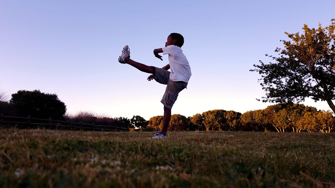 niño patea una pelota de rugby y luego corre fuera de la pantalla