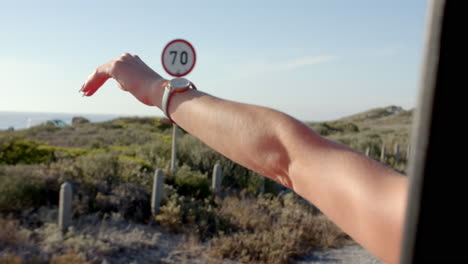 A-person's-arm-is-extended-out-of-a-car-window,-enjoying-the-breeze-on-a-road-trip-with-copy-space