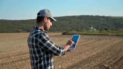 agricultor con tableta digital en un fondo de tractor arando en el campo. concepto de agricultura inteligente. imágenes de alta calidad 4k