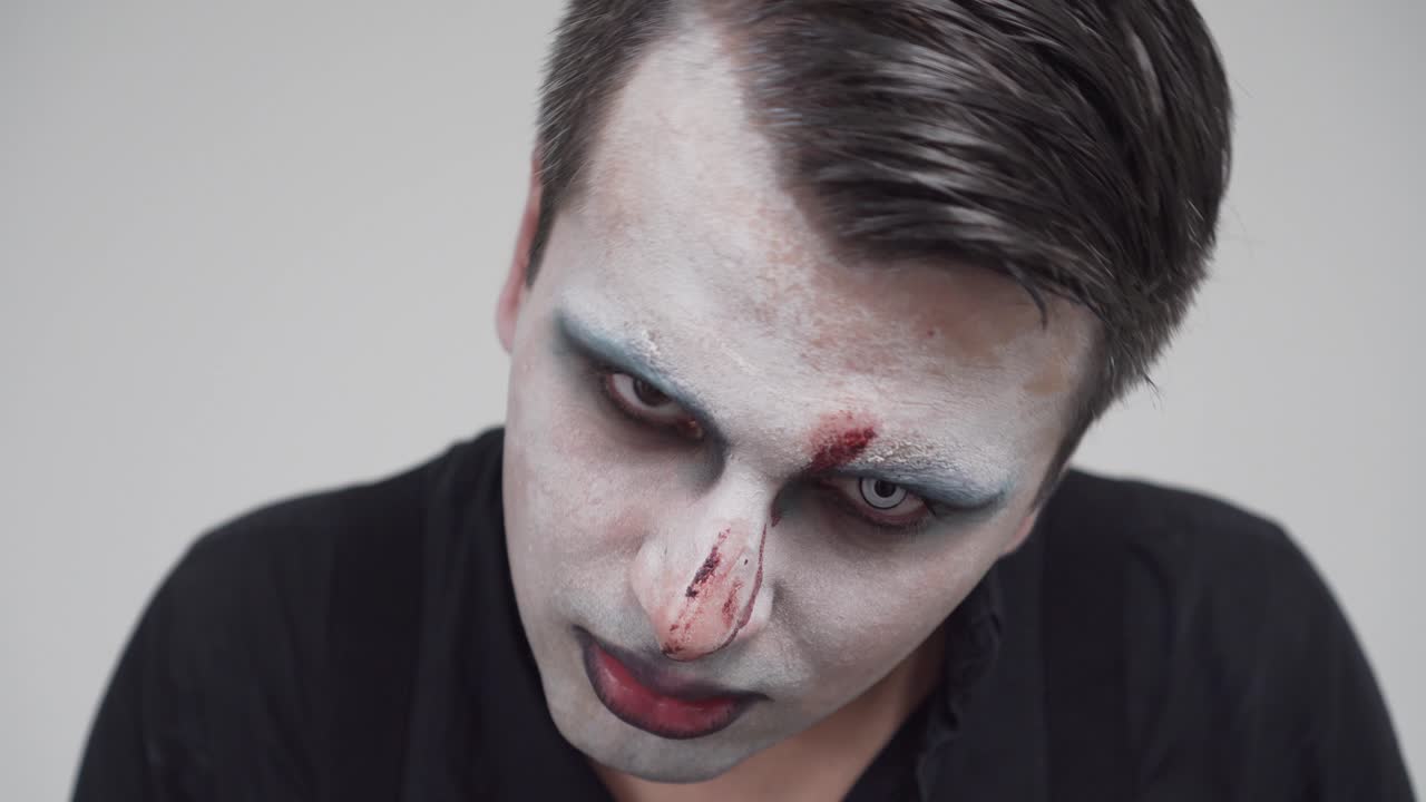 macho con pintura facial espeluznante mirando hacia arriba, retrato de primer plano