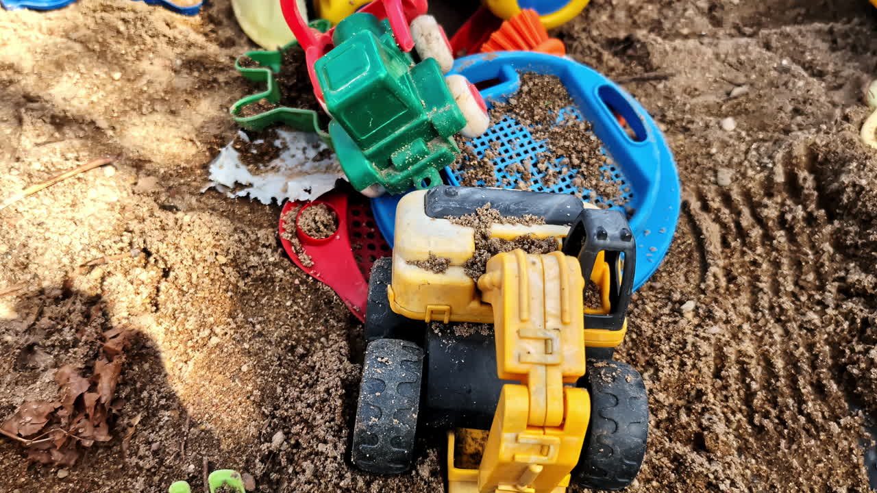 Closeup of sandbox with colorful toy trucks and children toys