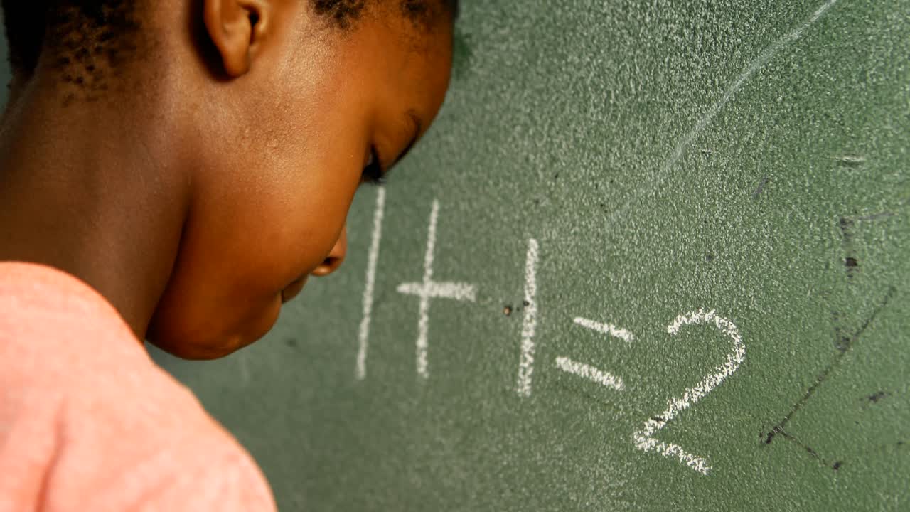 Schoolboy doing mathematics on chalkboard in classroom 4k