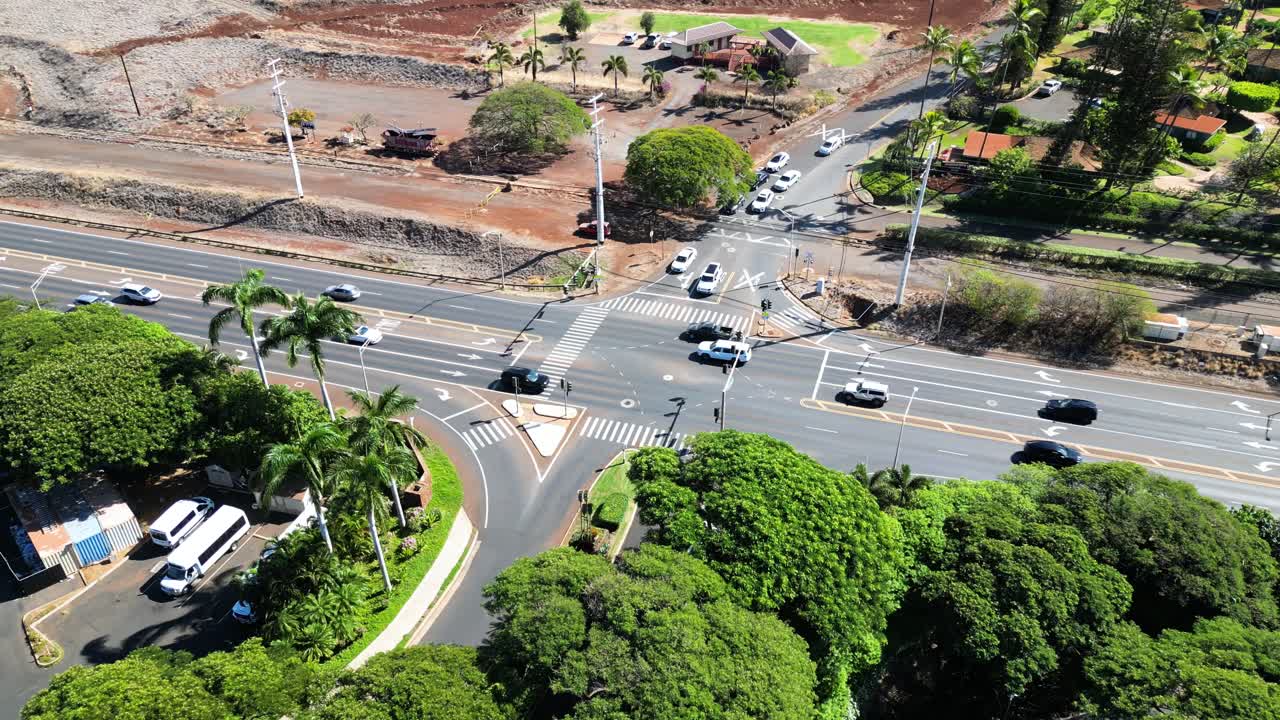 Drone circles a busy Maui junction as cars blur past on a tropical summer day