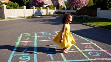 a young girl playing hopscotch on a sunny residential street