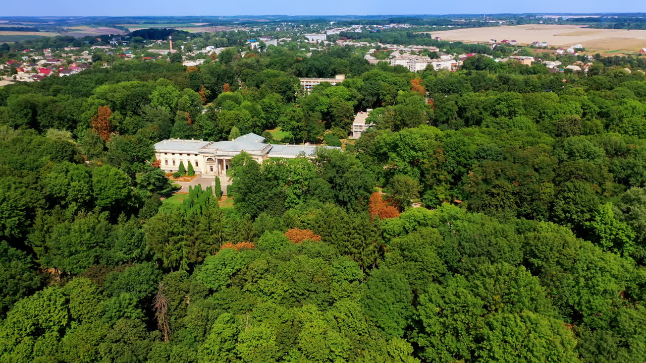 Lush greenery surrounding the beautiful historic palace. Urban landscape and farmlands at backdrop. Top view.
