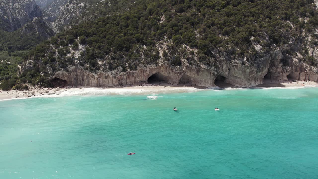 Scenic Turquoise Beach with Sea Caves, Cliffs, and Boats