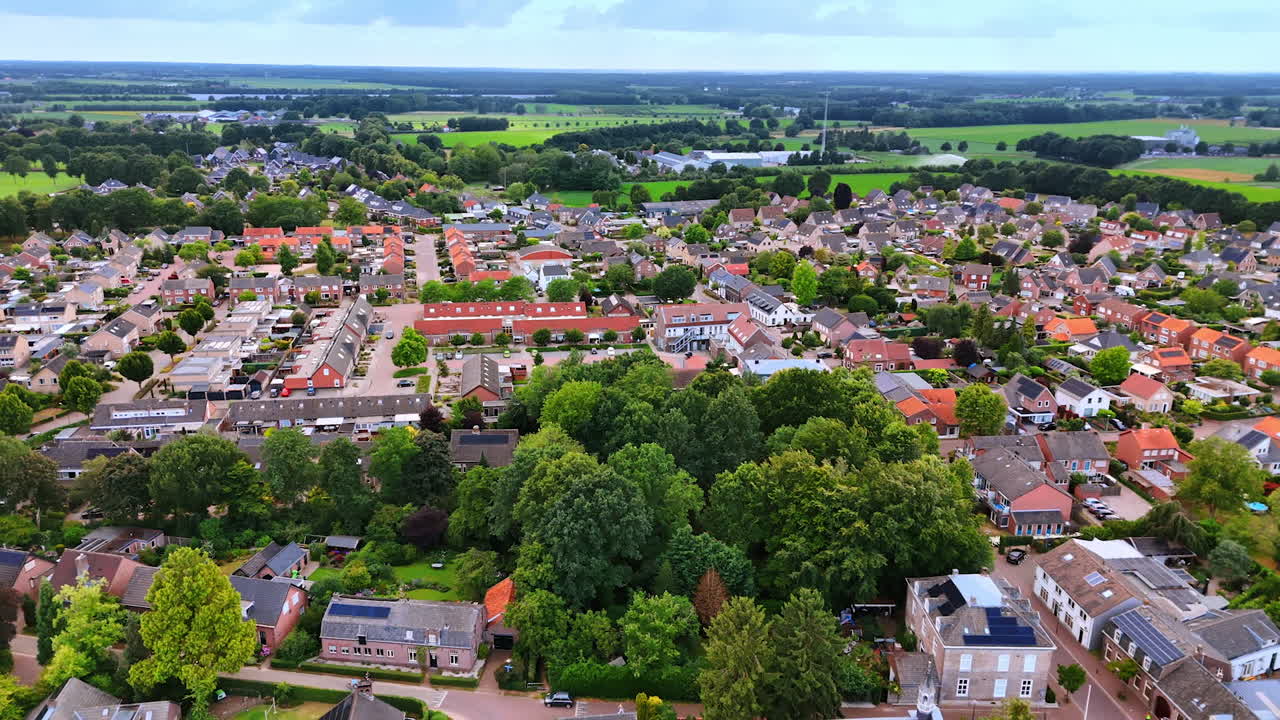 Drone view of Dutch town with red rooftops. Colorful aerial view of a Dutch town with red rooftops, green trees, and a peaceful countryside horizon
