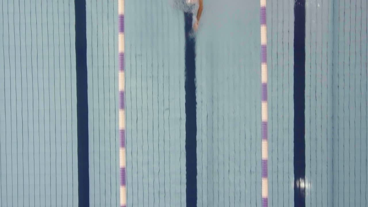 AERIAL SHOT OF A MAN SWIMMING IN A POOL