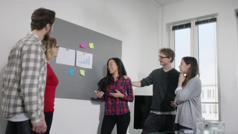 young multiethnic businesswoman presents chart on chalkboard to her colleagues